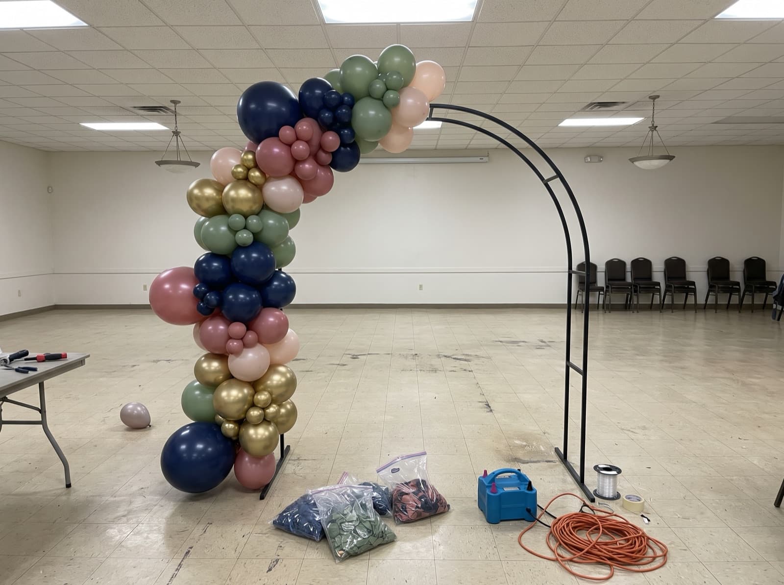 Organic balloon garland half-built on an arch frame before an event