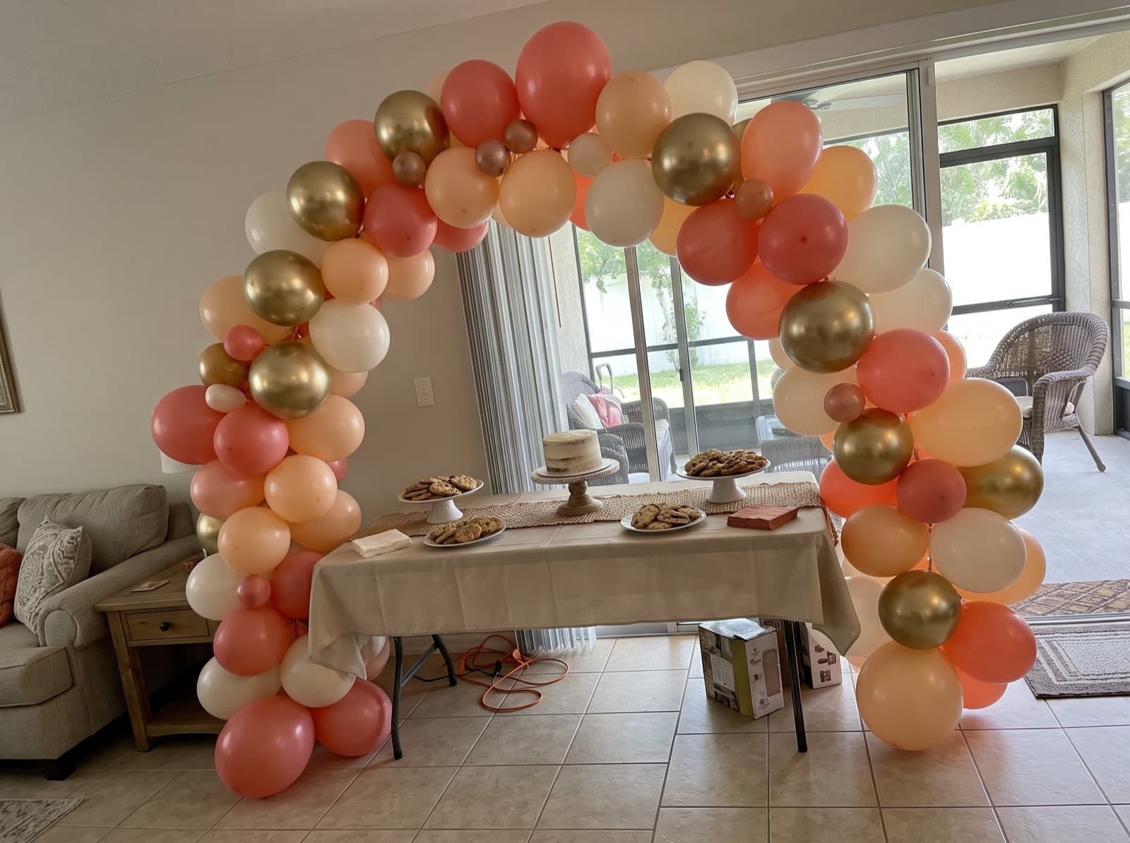 Organic balloon arch in coral, peach and ivory over a dessert table in an Orlando home