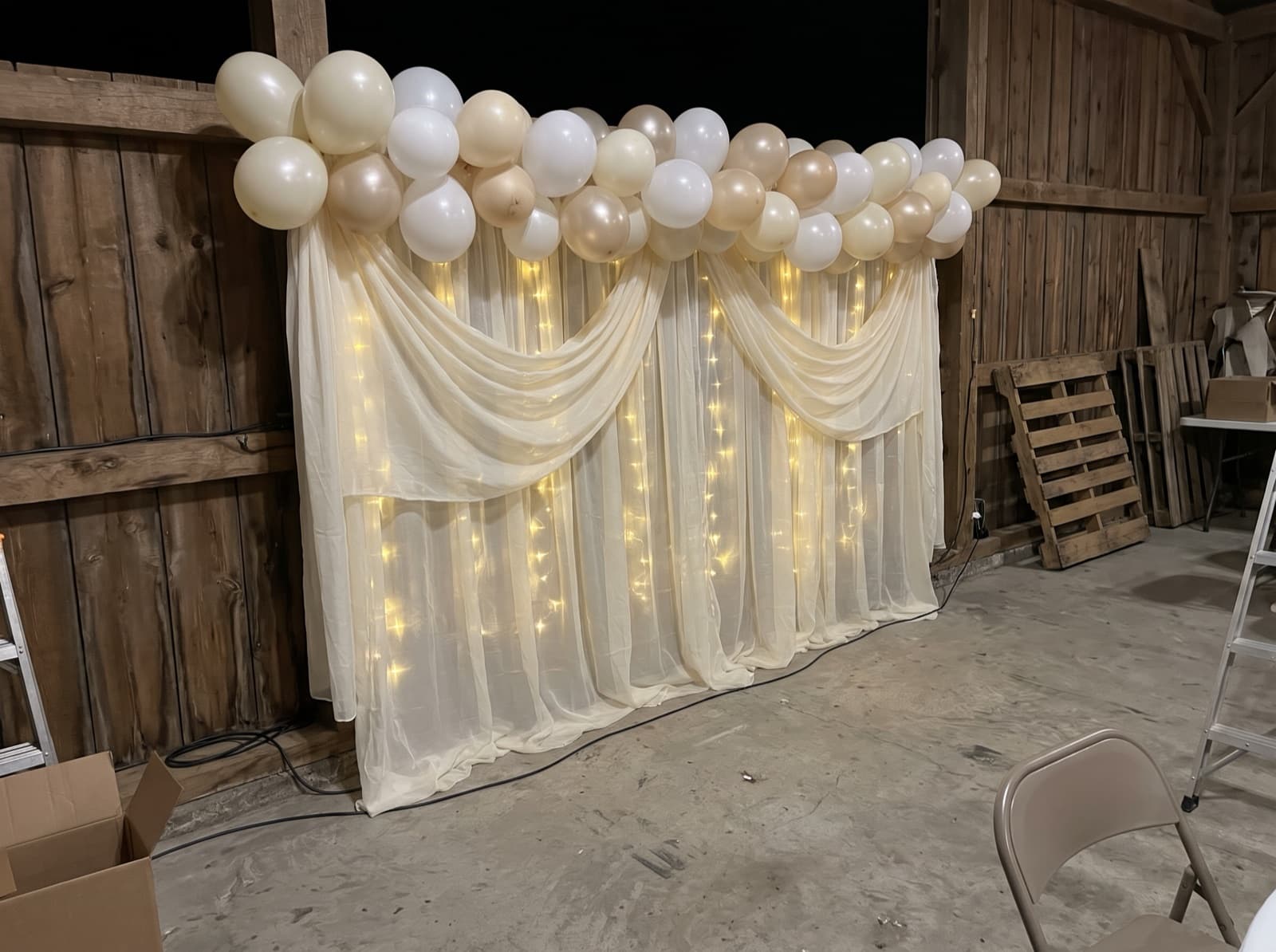 Draped backdrop with balloons and warm lights