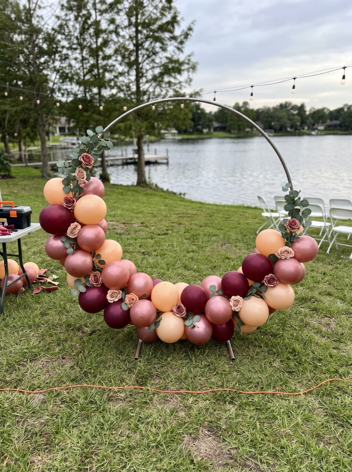 Balloon hoop backdrop with florals on a lakeside lawn