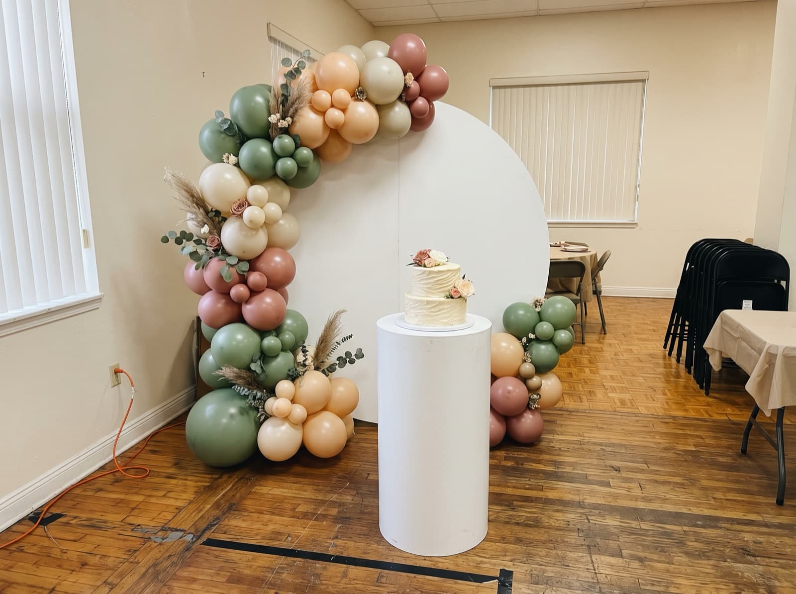 Round backdrop with a sage, peach and mauve organic balloon garland
