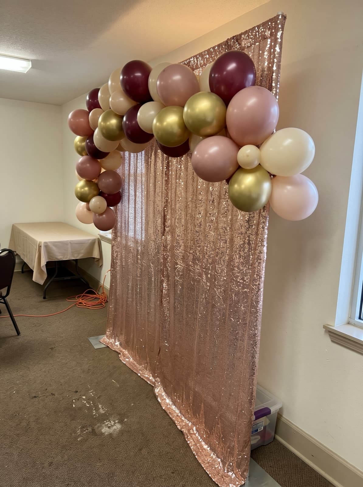 Rose gold shimmer wall backdrop with a balloon garland