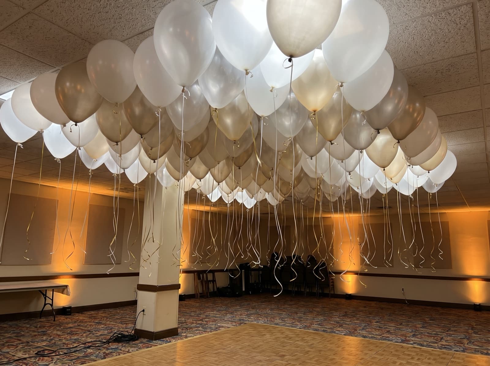 Balloon ceiling of white, clear and champagne balloons over a dance floor in an Orlando hotel ballroom